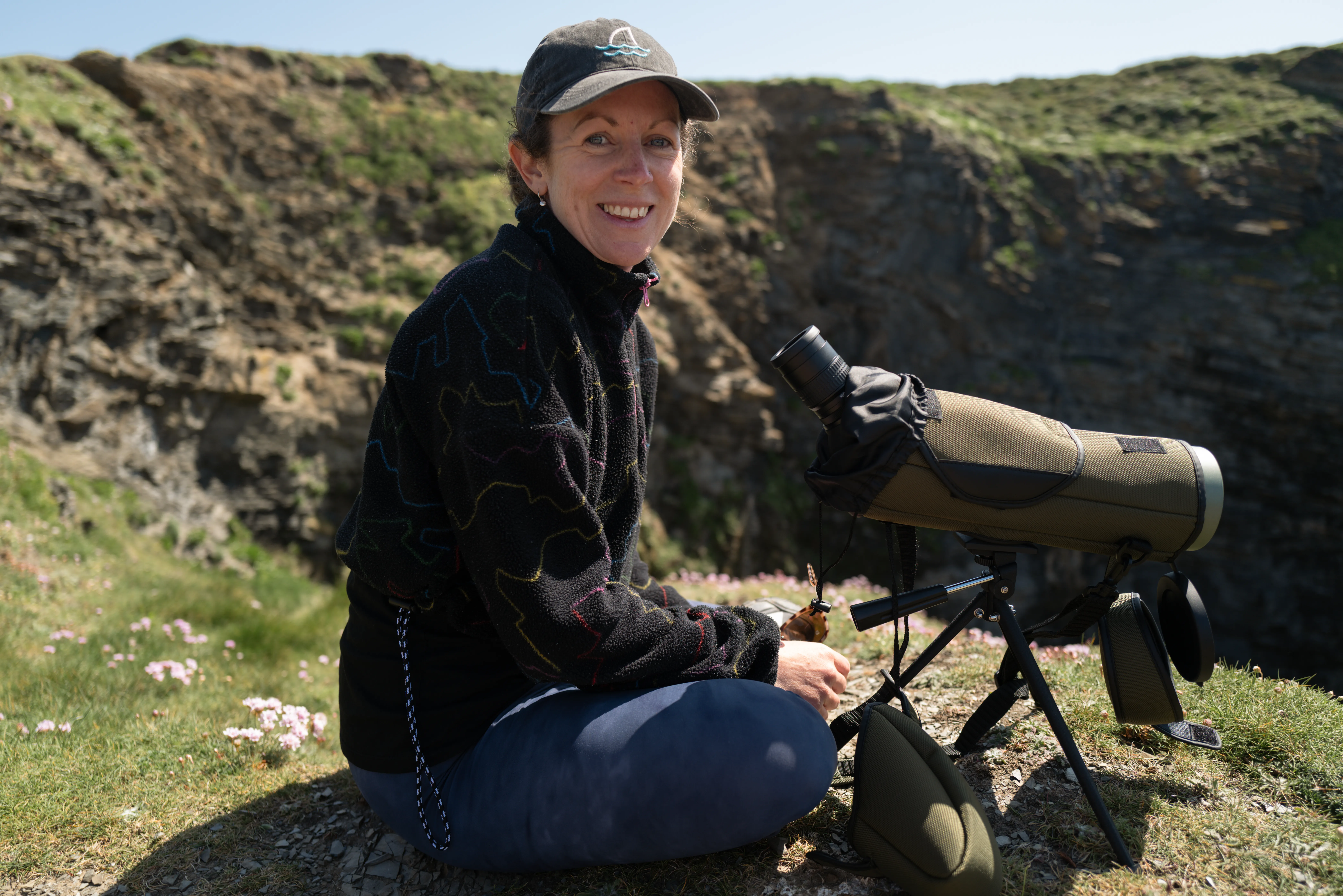Women on the coast path in Cornwall with binoculars, looking out to sea