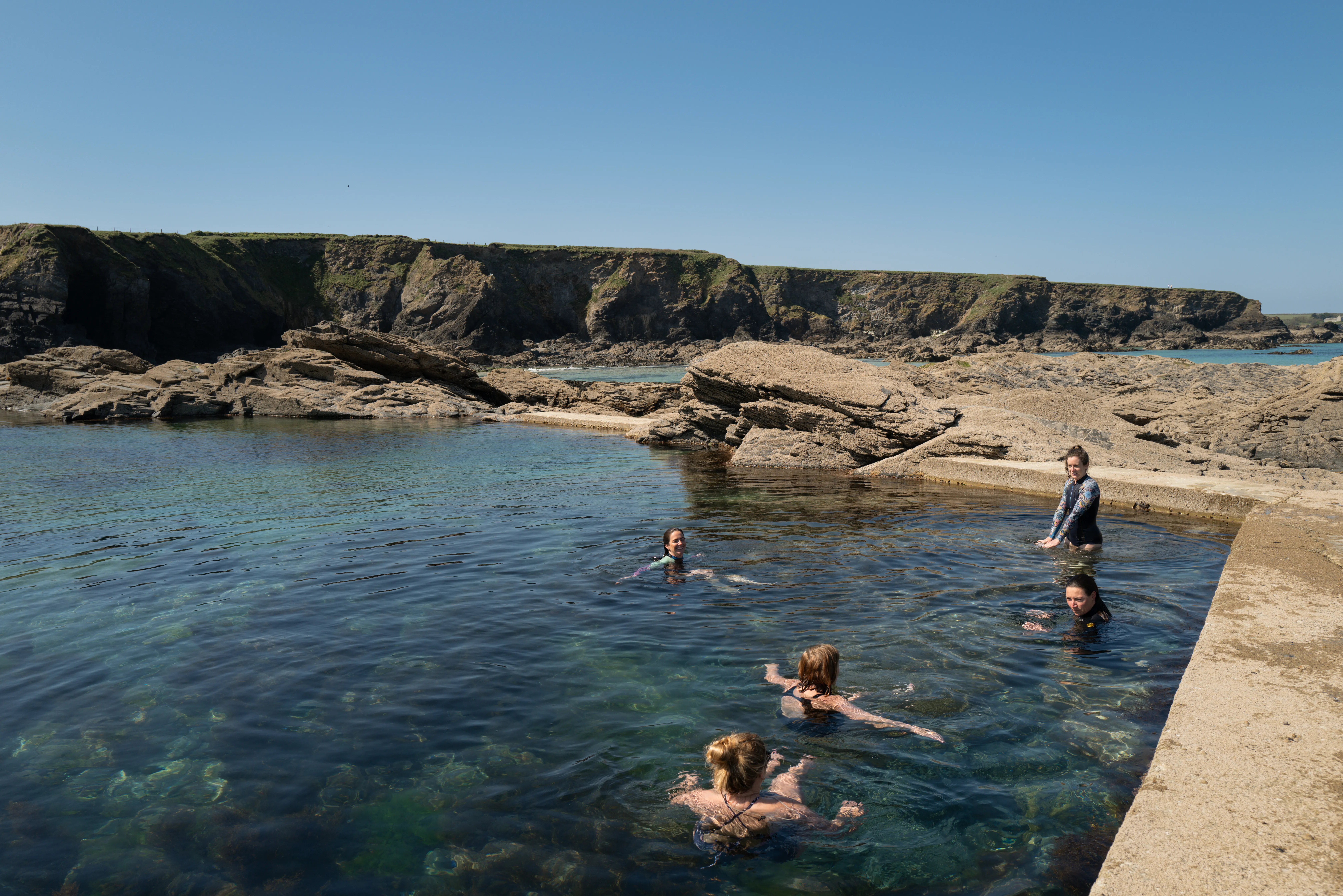 Women stepping into the sea for a swim on the Cornwall coast